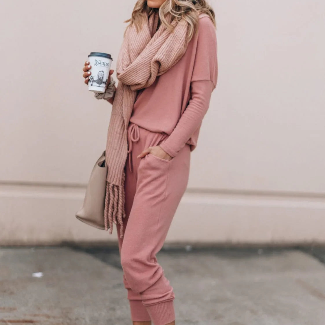 Side profile of a woman in a pink loungewear set with tapered joggers and ribbed cuffs, holding a coffee cup