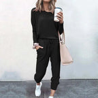 Woman modelling a black long-sleeve top and jogger set with white trainers and a pink handbag
