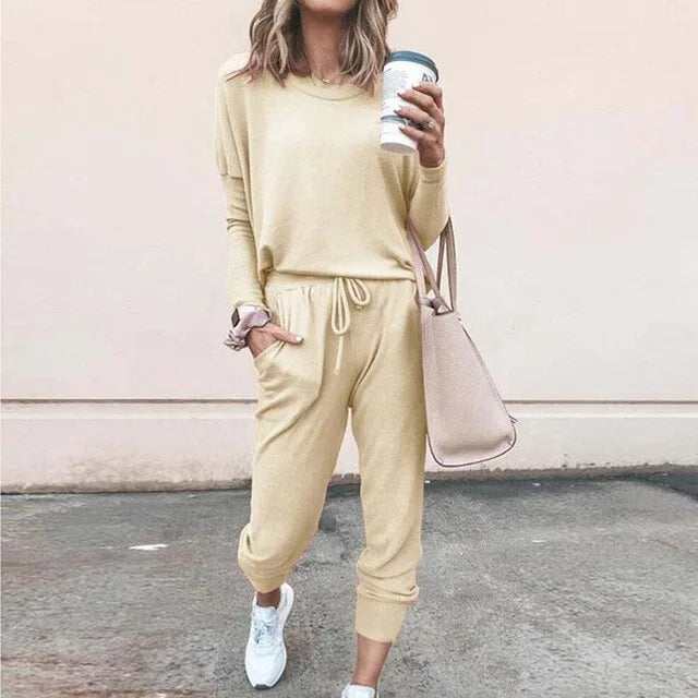 Woman wearing a pale yellow loungewear set with relaxed top and drawstring joggers, paired with white trainers