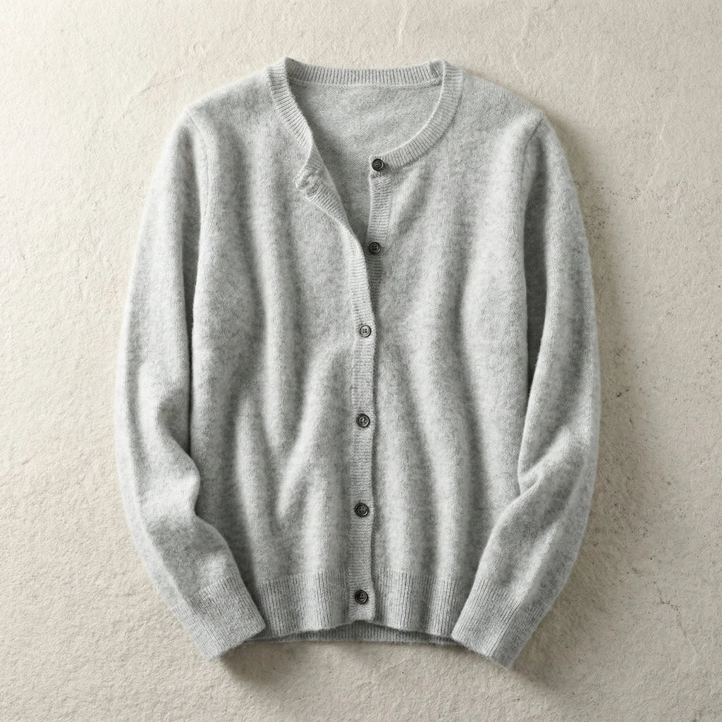 Light grey knitted cardigan laid flat with crew neckline and button front on a textured beige backdrop