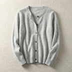 Light grey knitted cardigan laid flat with crew neckline and button front on a textured beige backdrop