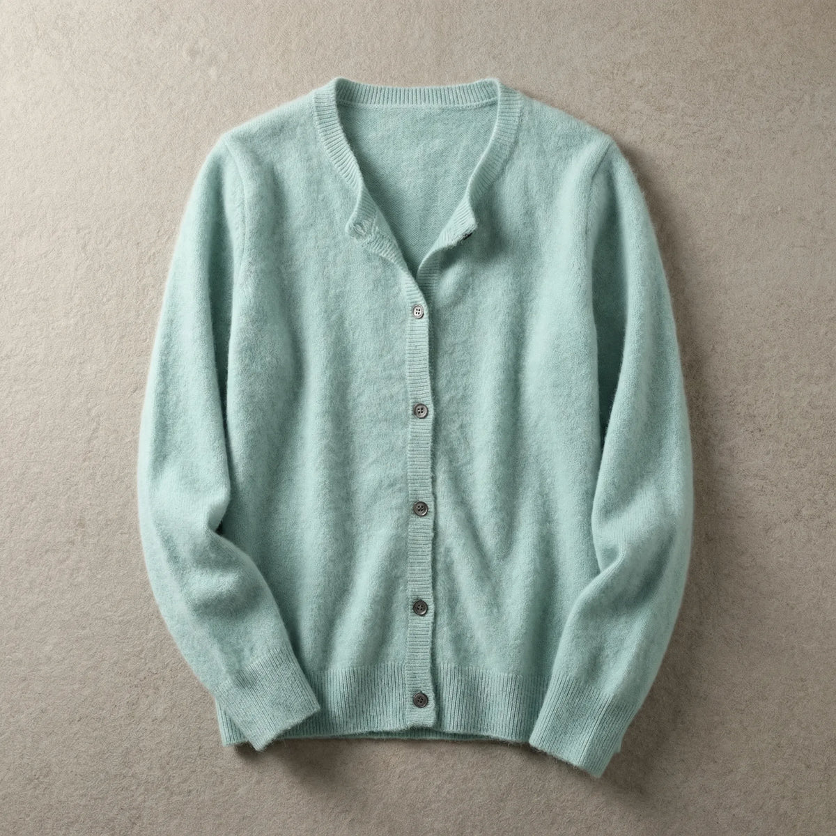 Mint green cardigan laid flat with crew neck, button placket and ribbed hem on a neutral backdrop