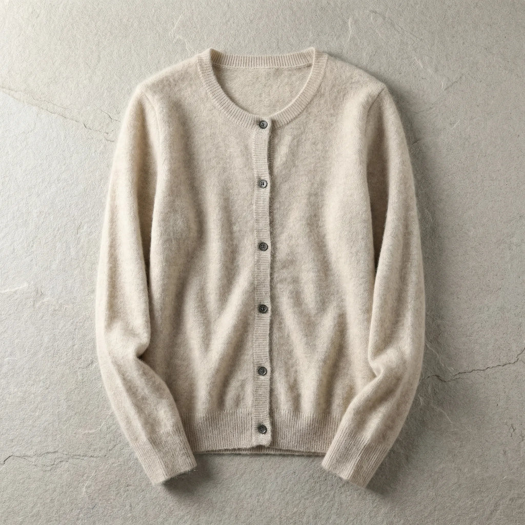 Beige cardigan laid flat showing crew neckline, button front and ribbed cuffs on a textured grey backdrop