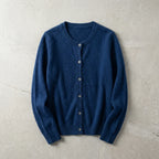 Navy blue cardigan laid flat showing crew neck, button placket and ribbed hem on a grey marble backdrop