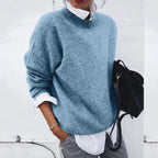 Close-up of a woman wearing a soft blue knit jumper with a mock neck, layered over a white shirt collar.