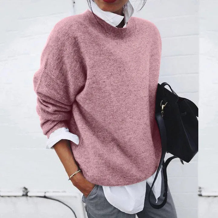 Pink mock neck jumper with a relaxed, slouchy fit, paired with grey trousers and a black backpack.