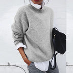 Light grey knitted jumper shown layered over a crisp white shirt, with long sleeves pushed up slightly.