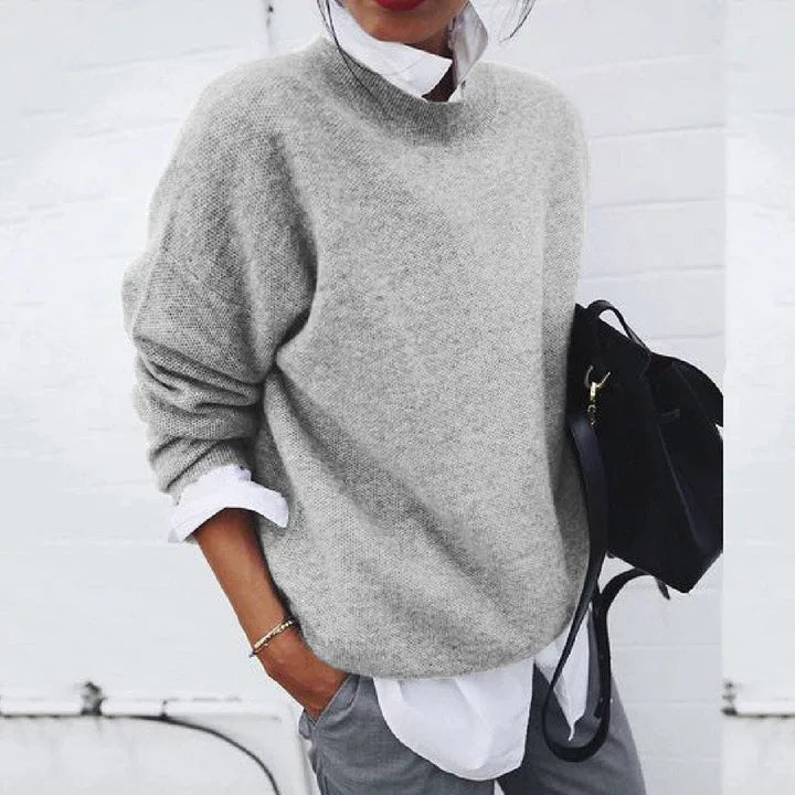 Light grey knitted jumper shown layered over a crisp white shirt, with long sleeves pushed up slightly.