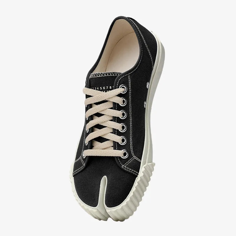 Top-down view of a black canvas split-toe trainer with cream laces and ribbed off-white rubber sole