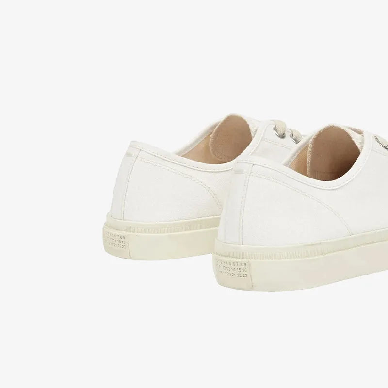 Close-up angle of the white canvas upper highlighting the split-toe shape and silver eyelets