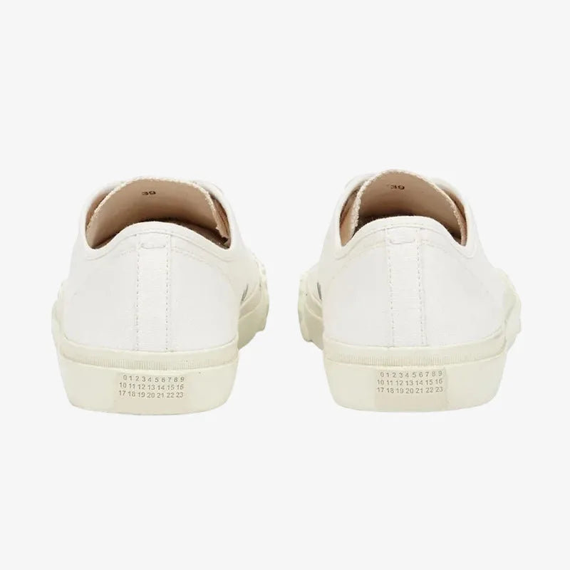Detail shot of white split-toe trainer sole showing the ribbed tread and cream canvas panel stitching