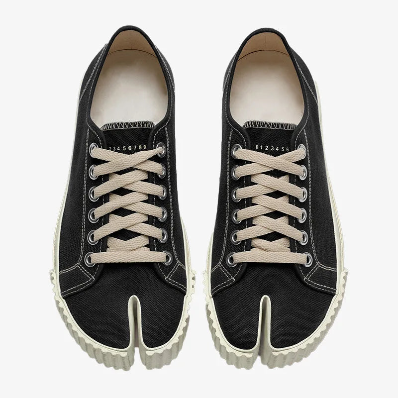 Overhead view of a matching pair of black split-toe canvas trainers with numbered heel tab and cream laces