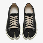 Overhead view of a matching pair of black split-toe canvas trainers with numbered heel tab and cream laces