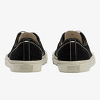 Back view of a black canvas trainer pair showing the numbered size chart label and ribbed sole edge