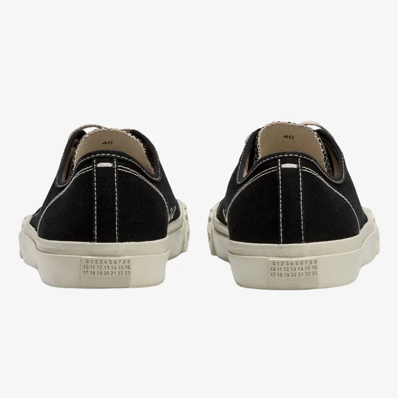 Back view of a black canvas trainer pair showing the numbered size chart label and ribbed sole edge