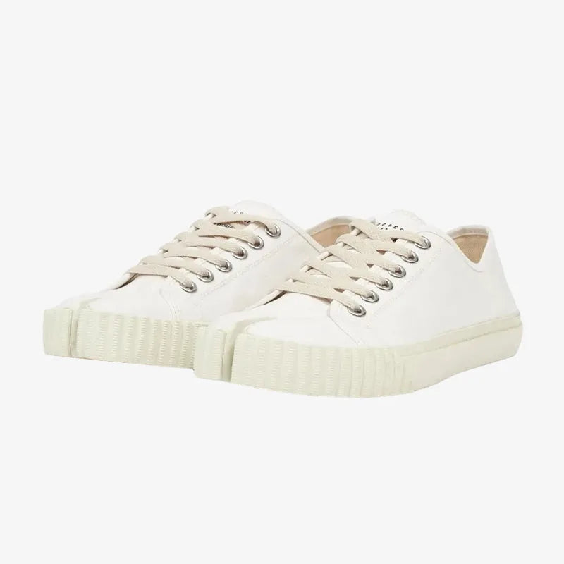 Angled pair view of white canvas split-toe trainers with cream laces and cream ribbed rubber sole