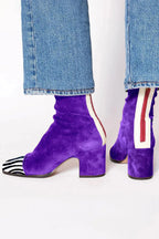 Rear detail of purple suede block-heel boot showing cream and red stripe panel at the heel seam