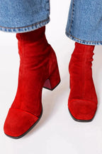 Close-up back view of purple suede boots showing the red zip and cream leather stripe detail