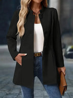 Black stand-collar coat with fabric-covered buttons styled open over a white camisole and denim