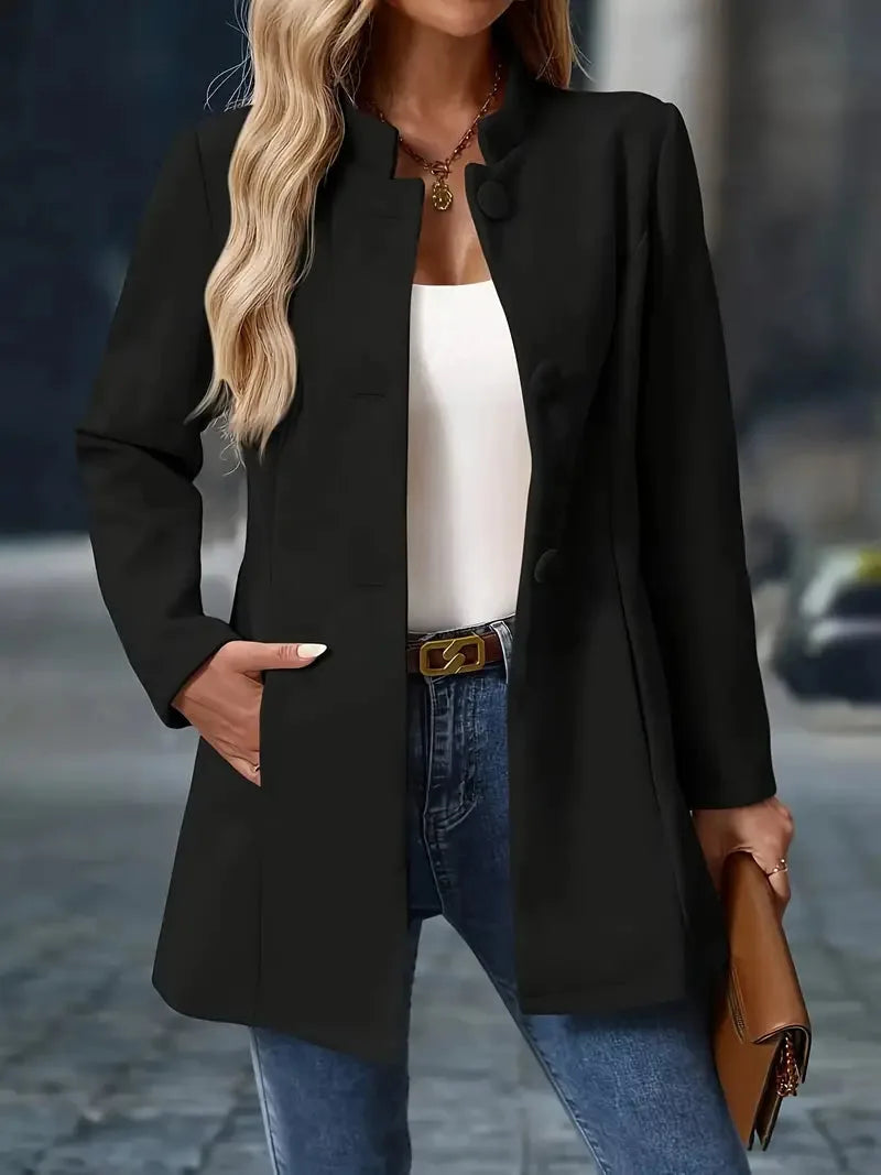 Black stand-collar coat with fabric-covered buttons styled open over a white camisole and denim