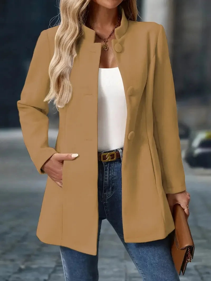 Camel stand-collar coat with tonal buttons, shown open with hands in pockets over jeans