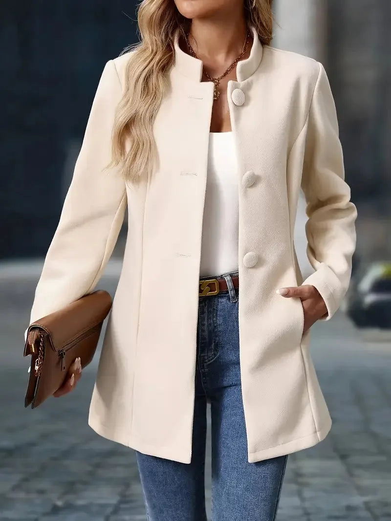Three-quarter view of the cream coat highlighting the fitted waist and long sleeves