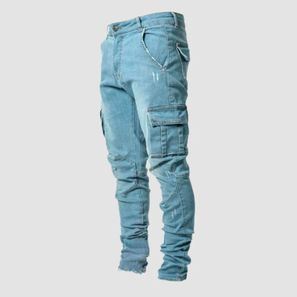 Side view of light blue stretch denim cargo jeans with a large flap cargo pocket on the thigh and distressed detailing.