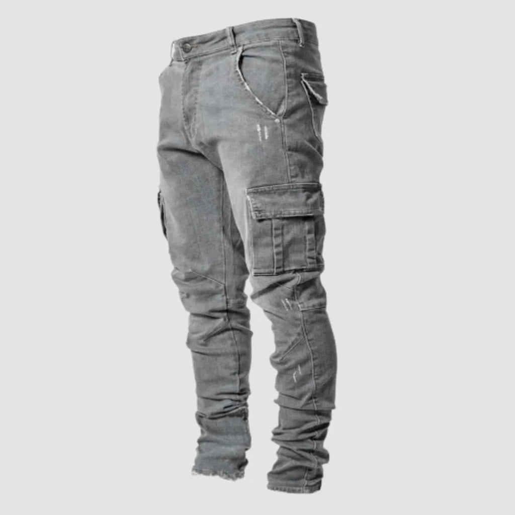 Grey washed denim cargo jeans shown from the side, highlighting the tapered leg and stitched flap pocket.