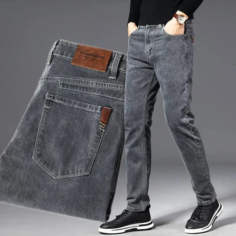 Man wearing slim grey jeans with black jumper, paired with folded denim showing front zip and back pocket