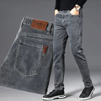 Man wearing slim grey jeans with black jumper, paired with folded denim showing front zip and back pocket