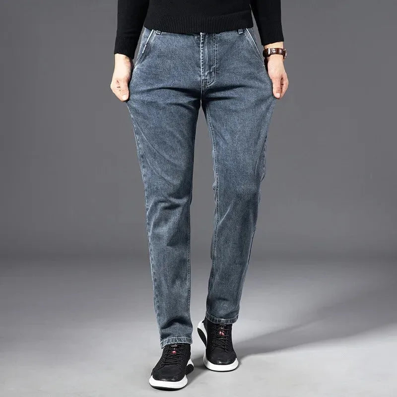 Man wearing slim blue-grey jeans with black jumper, front view showing tapered fit and zip fastening