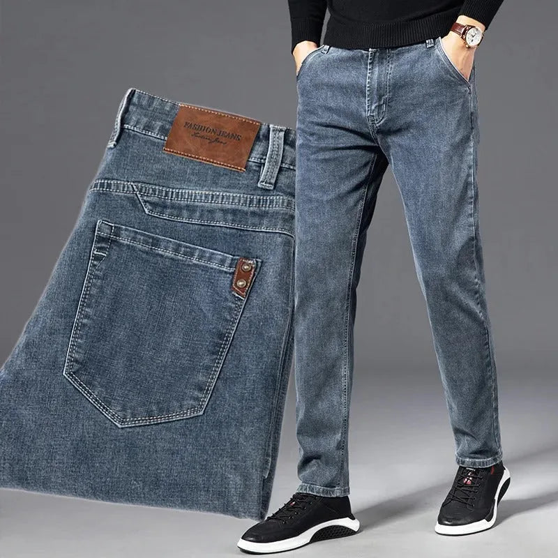 Man wearing slim blue denim jeans with black jumper, paired with folded pair showing pocket and label detail