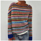 Close-up of a multicolour striped knit jumper with blue ribbed cuffs, worn with jeans against a plain backdrop