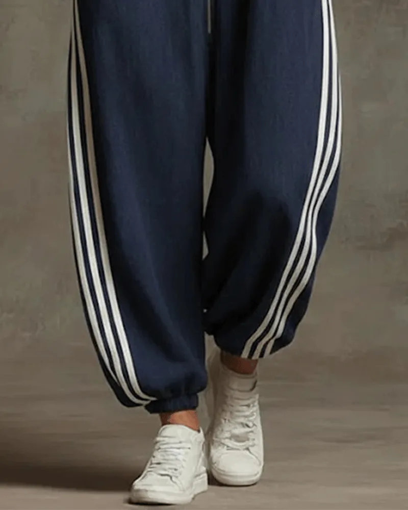 Close-up of the double stripe side detailing running down the wide-leg trousers of the dark blue jumpsuit