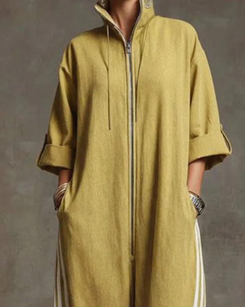 Close-up of the stand collar and silver zip closure on a mustard yellow jumpsuit worn with statement earrings