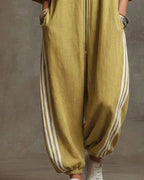 Rear view of the mustard yellow jumpsuit showing the relaxed drape and side stripe detail on the trousers