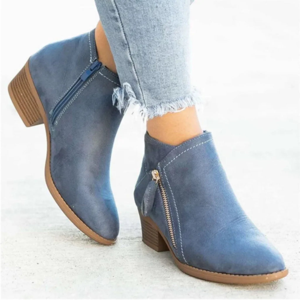 Side view of blue suede ankle boot worn with cropped jeans, showing stacked block heel and side zip
