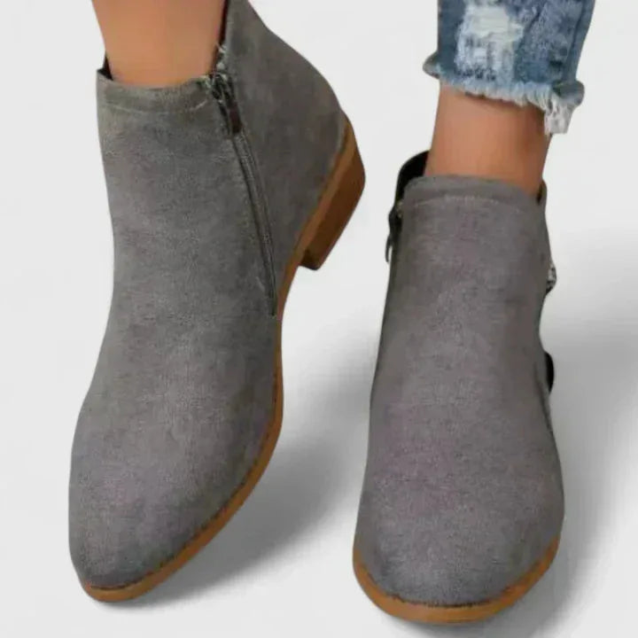 Grey suede ankle boots shown up close, focusing on the rounded toe and side zip pull