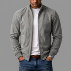 Grey suede bomber jacket worn open over a white t-shirt, hands in jean pockets