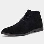 Angled studio shot of a single black suede chukka boot showing pointed toe and contrast stitched sole