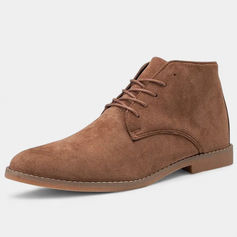 Angled studio shot of a single tan suede chukka boot with pointed toe and matching tonal sole