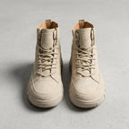 Front view of a pair of beige suede combat boots with fabric lace panel and canvas pull tab
