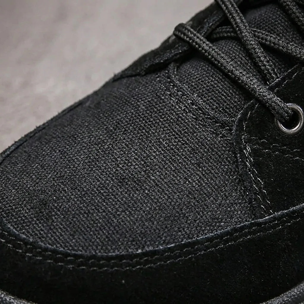 Close-up of the black fabric eyelets, laces and toe cap stitching on the boot upper