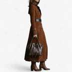 Side profile of caramel suede trench coat cinched with a wide black belt at the waist