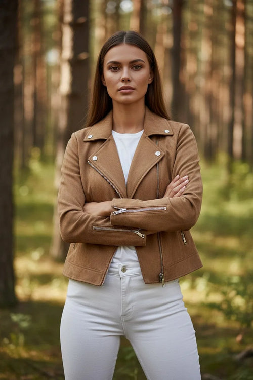 Front view of a tan suede-effect biker jacket worn over a white top and white jeans, arms crossed showing zip cuffs.