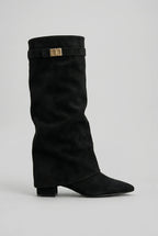 Side view of a black suede-effect knee-high boot with slouchy fold-over shaft and gold-tone buckle strap