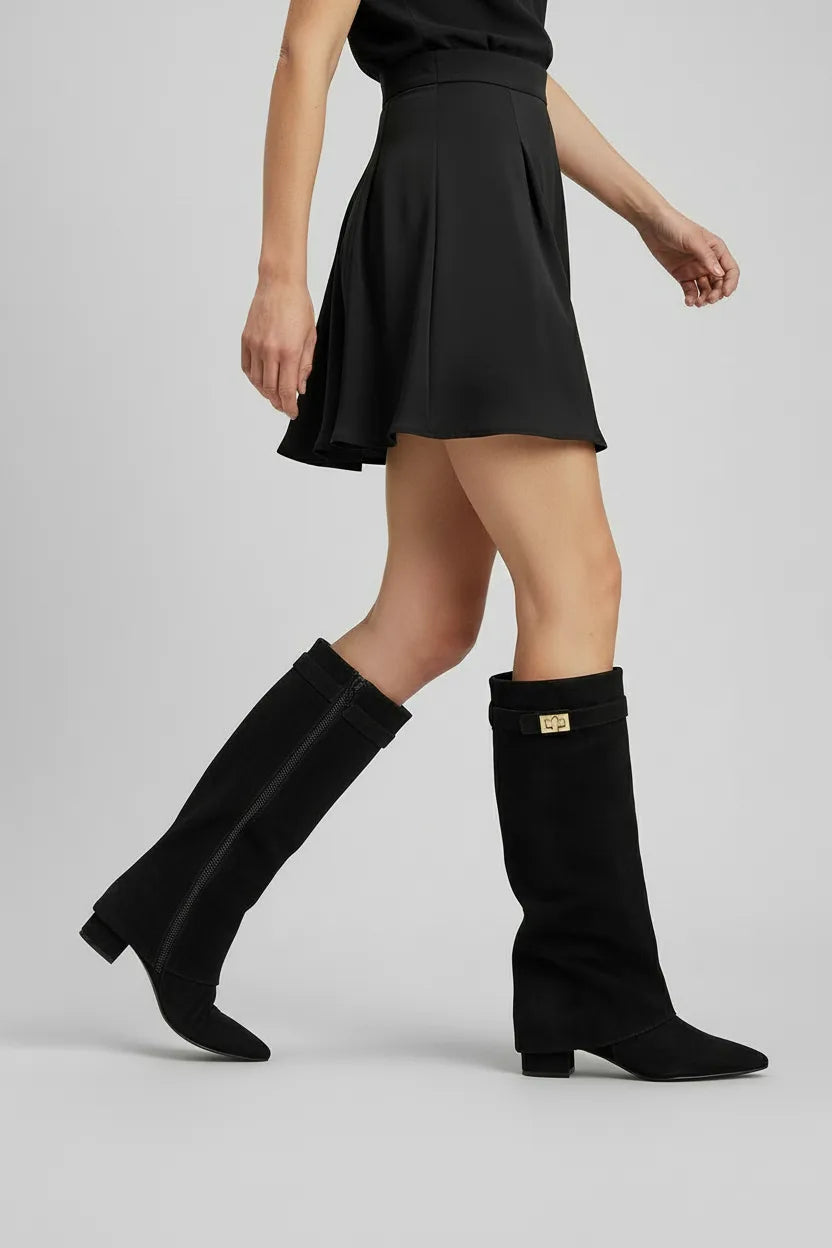 Woman walking in black slouchy knee-high boots with pointed toe, styled with a flared black mini skirt