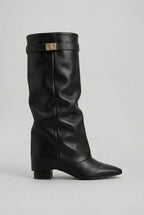 Side profile of a black leather-look knee-high boot with pointed toe and stacked block heel