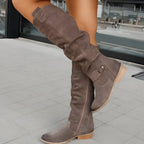Side view of taupe grey suede knee-high slouch boots with buckle strap and stacked wooden heel