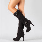 Side view of black suede knee-high stiletto boot with slouched shaft and dual ring buckle detail
